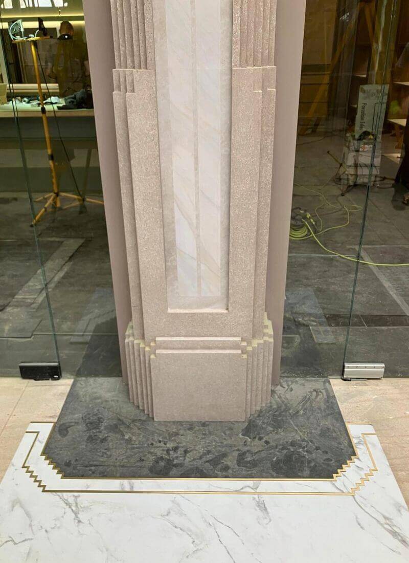 Man vs Baby - Column Base Detail – Scenic Stone Finishes Close-up of a column base showing layered scenic stone effects and contrasting floor finishes.